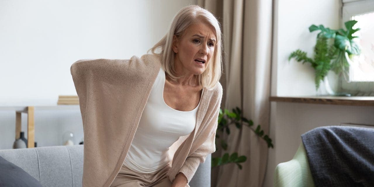 old woman touching her back when trying to stand