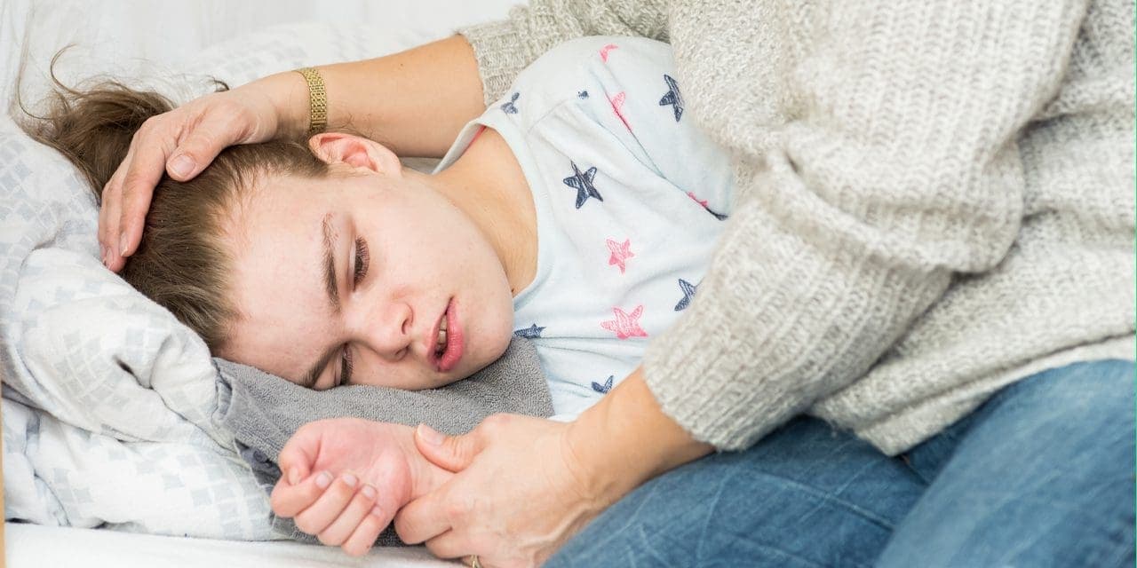 a girl lying comforted by her mother