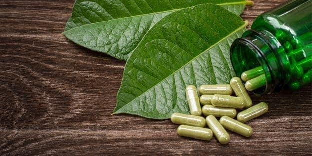 kratom leaves and green capsules