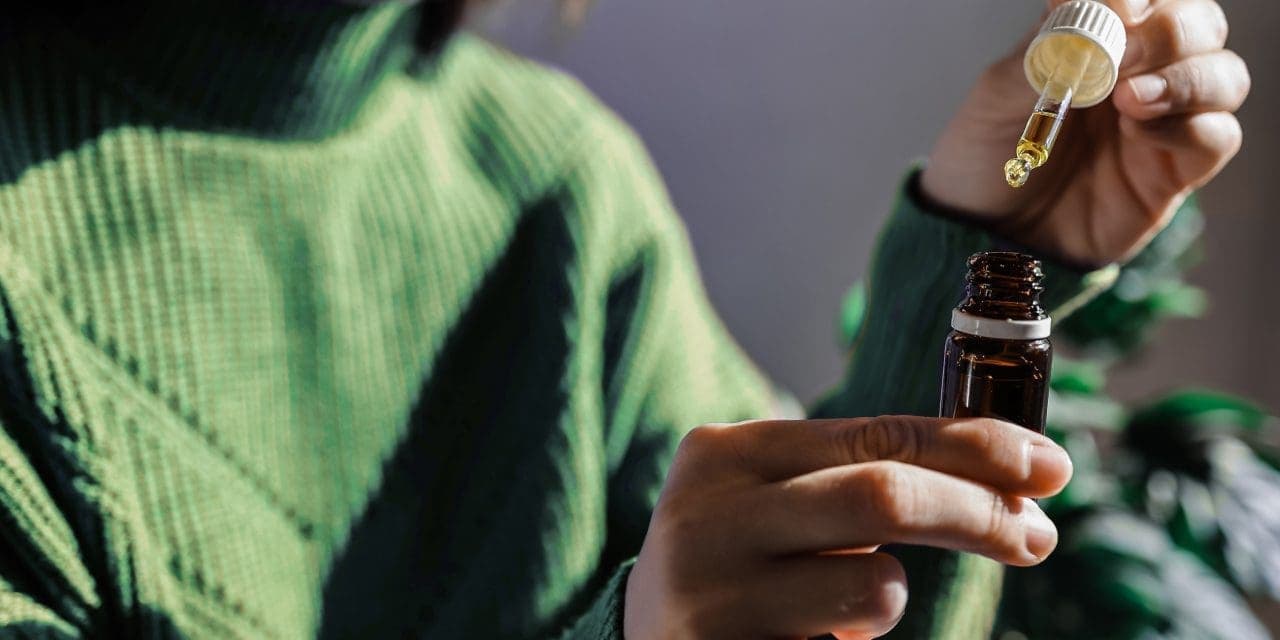 a woman holding a bottle and dropper